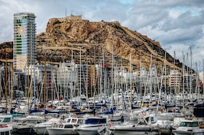 A marina with numerous boats docked, a prominent building labeled "GRAN SOL," and a rocky hill in the background.
