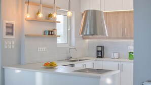 A modern kitchen with white cabinetry, stainless steel appliances, and pendant lighting. - Unique Sea View,Sunset with Privacy! Bedrooms with ensuite bathroom,Jacuzzi,GYM (Rethymno)