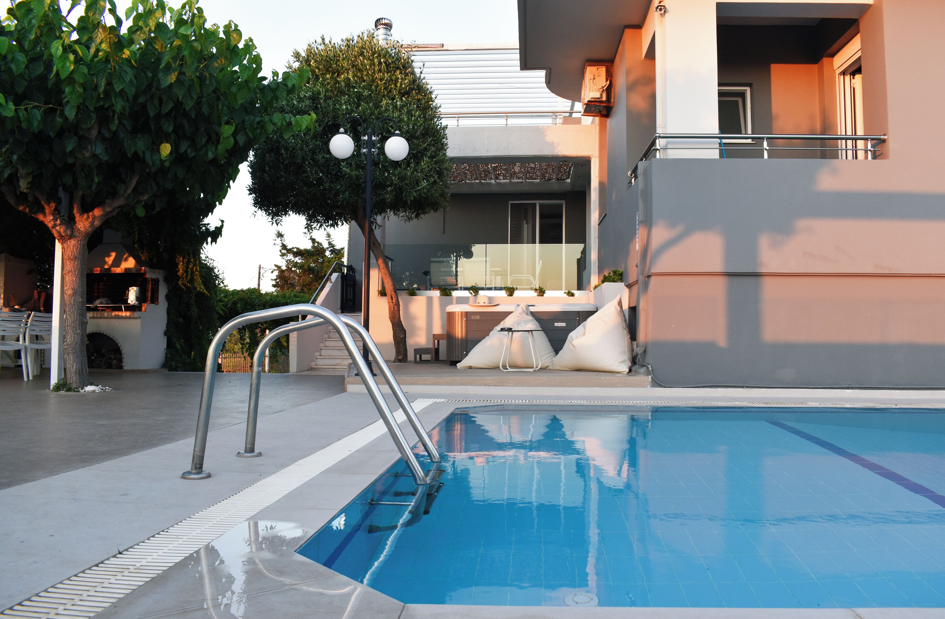 Une piscine avec un escalier en métal, un arbre et un bâtiment doté d’un balcon en arrière-plan.