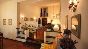 Un salon chaleureux avec un canapé, une table basse et des objets de décoration. Un escalier mène à l’étage supérieur.