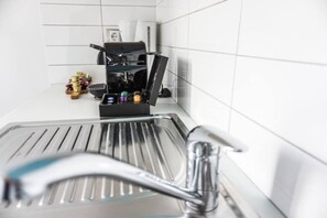 A kitchen with a coffee machine, a sink, and a countertop with various items. - Echoes of inspiration & calmness! `Urban  Blue` (Rethymno)