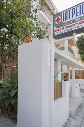 A medical office building with a signboard, a white exterior wall, and a staircase leading to an upper level.