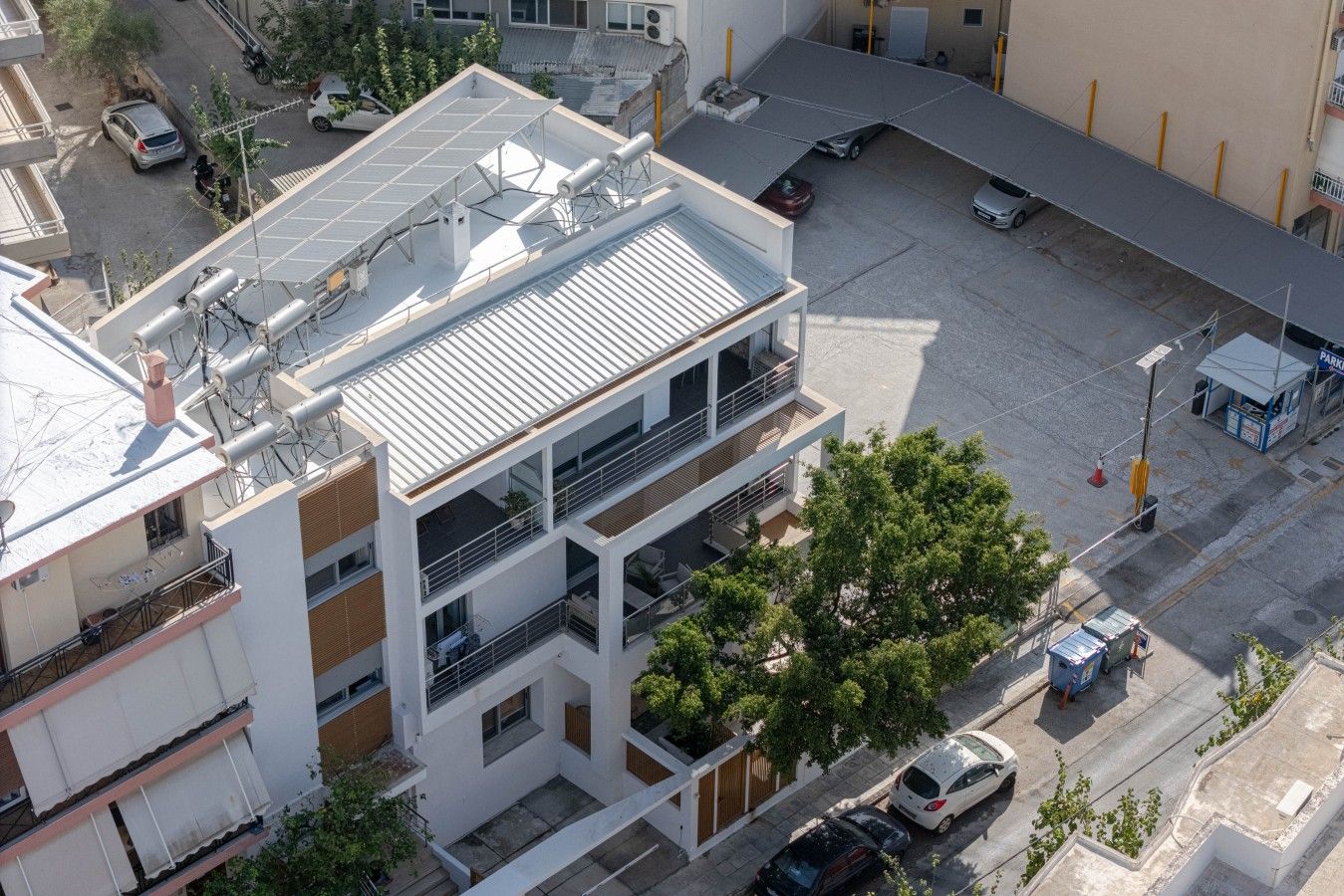 A multi-story building with a flat roof, solar panels, and a parking area.