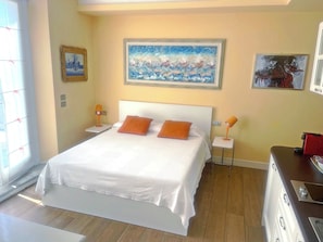 Een hotelkamer met een groot bed, twee nachtkastjes en een schilderij erboven.