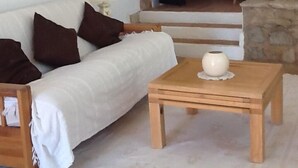 Una sala de estar acogedora con un sofá blanco, una mesa de centro de madera y una pared de piedra.