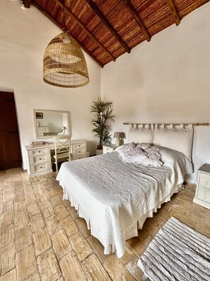 A bedroom with a large bed, a bedside table, a nightstand, a mirror, and a hanging light fixture. - Stunningly Restored Farmhouse With Private Pool, Panoramic Views & Large Garden (Barranco De Sao Miguel, Azinheiro)