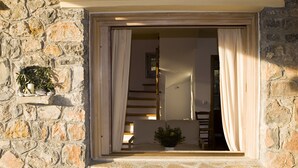 Un muro de piedra con una ventana, un banco de madera y una planta en maceta.