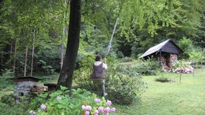 Una persona en un área boscosa con una estructura de piedra y una cabaña de madera.