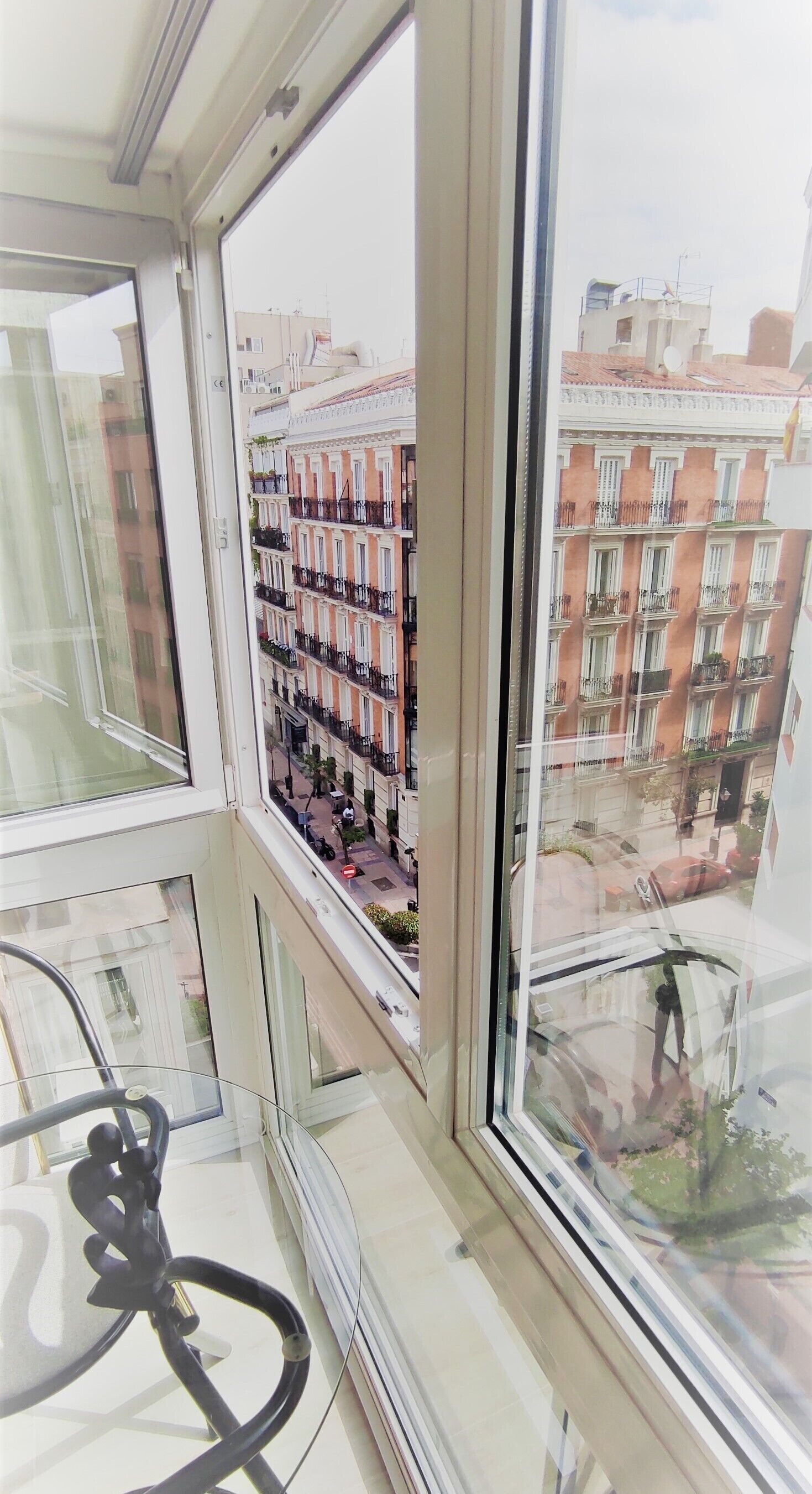 Une vue depuis une fenêtre d’un immeuble de grande hauteur, donnant sur une rangée de maisons mitoyennes dotées de balcons.