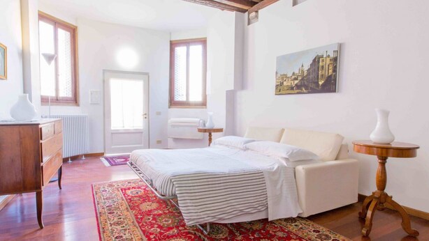 Une chambre à coucher avec un lit, une commode, un radiateur et une fenêtre.