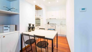 Une cuisine compacte avec des meubles blancs, un îlot central et des appareils électroménagers modernes.