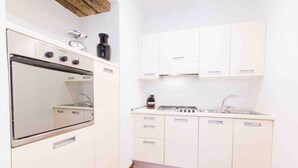 Une cuisine de taille réduite, avec des meubles blancs, une cuisinière et un évier.