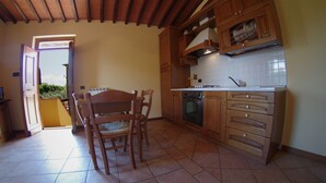 Une cuisine avec des meubles de rangement en bois, un pare-feu en carrelage et un coin repas comprenant une table et des chaises.