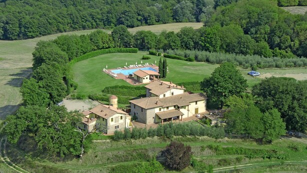 Vue aérienne d’une propriété située à la campagne, avec une grande maison, une piscine et un environnement verdoyant.