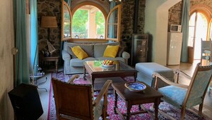 A cozy living room with a stone wall, wooden furniture, and a large window.