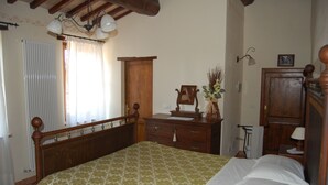 A bedroom with a wooden bed frame, a bedside table, a dresser, and a mirror.