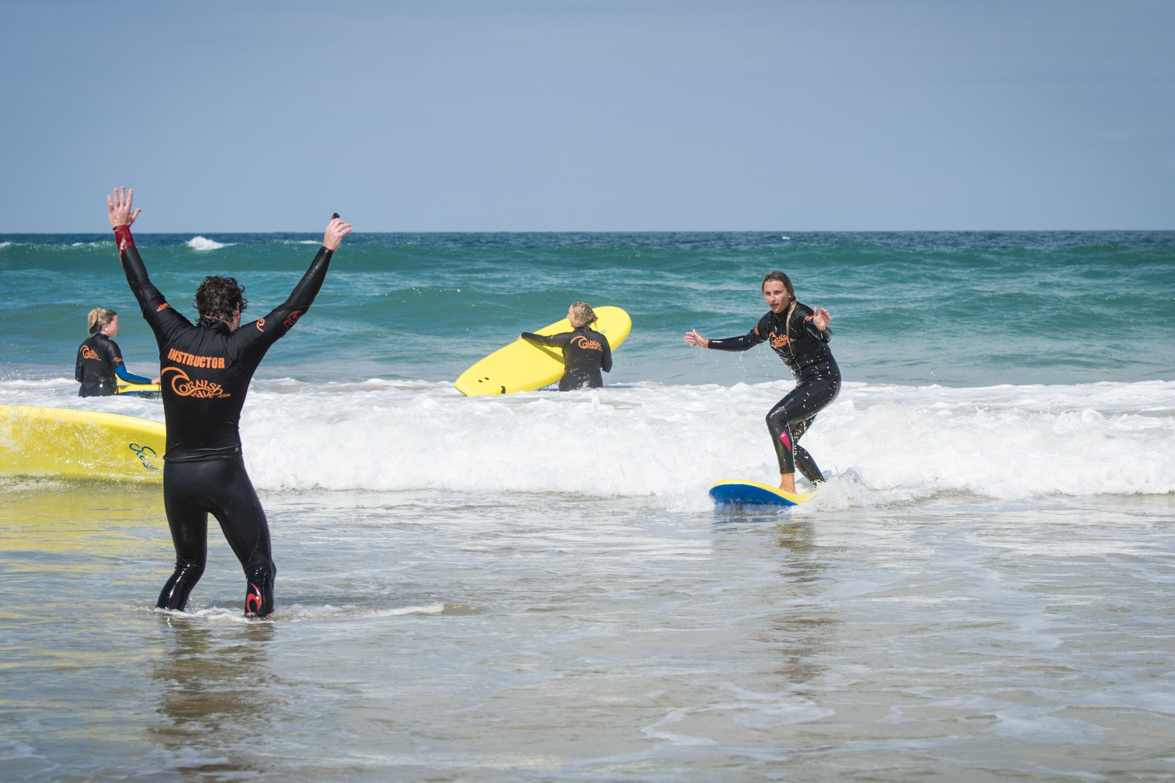 Un grupo de personas con trajes de neopreno en una playa, con tablas de surf.