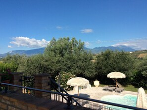 A pool area with a view of mountains, surrounded by greenery and outdoor furniture. - "Casale Giacinta" ancient cottage between sea and mountains with swimming pool (Pianella (PE))