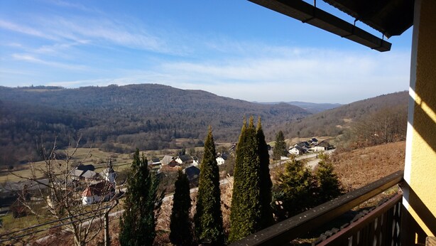 Un balcón con vistas a un valle, casas y árboles.