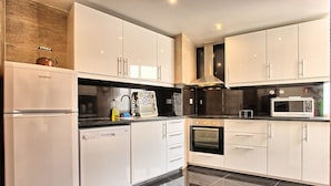 Una cocina moderna con armarios blancos, lavavajillas, horno y microondas.