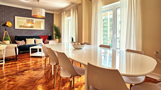 Un comedor moderno con una mesa grande, sillas y una araña.