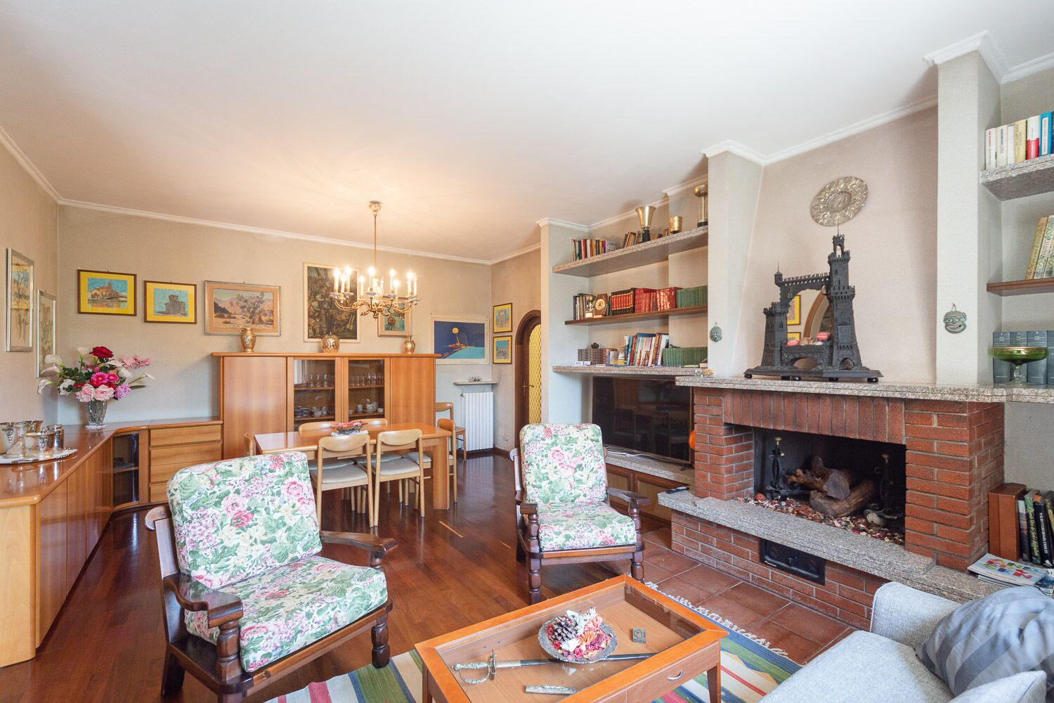 A cozy living room with a fireplace, wooden furniture, and a bookshelf.