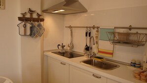 Eine Küche mit Spüle aus Edelstahl, einem Wasserkocher und verschiedenen Küchenutensilien, die an der Wand hängen.