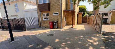 A residential street with houses, a gated driveway, and a sidewalk.