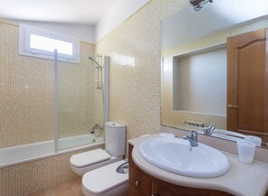 A bathroom with a bathtub, toilet, sink, and a large mirror.