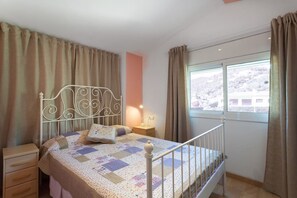 A bedroom with a bed, nightstand, and window with curtains.