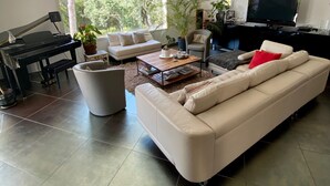 A modern living room with a piano, sofas, a coffee table, and a TV. - modern luxery home (Fréjus)