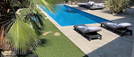 A swimming pool with lounge chairs and a pergola.