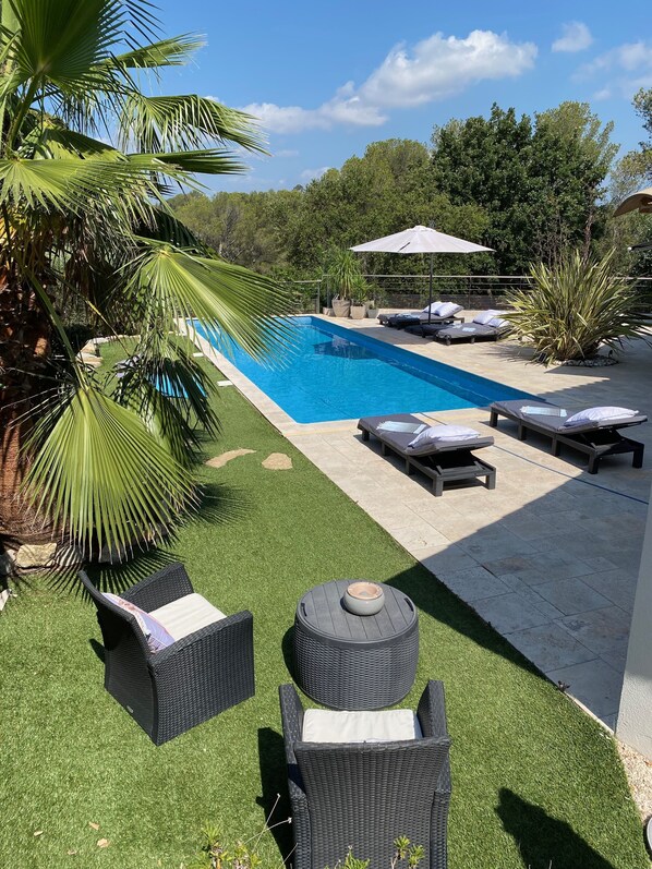 A swimming pool with lounge chairs and a pergola.