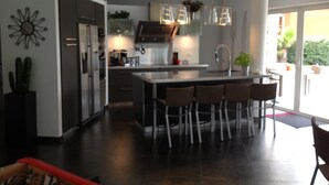 A modern kitchen with a central island, bar stools, and pendant lighting. - modern luxery home (Fréjus)