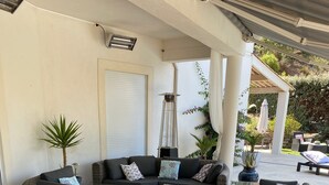 A covered outdoor seating area with wicker furniture, a glass coffee table, and potted plants. - modern luxery home (Fréjus)