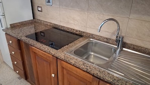 A kitchen with granite countertops, a stainless steel sink, wooden cabinets, and a built-in electric stove. - Villa Giuliana, small two-room apartment 3/4 Ptl. (Capoliveri (LI))