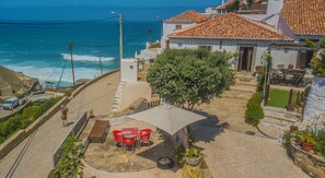 A coastal property with a paved patio, outdoor seating, and a view of the ocean.
