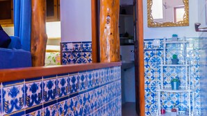 Een kamer met een houten plafond, een betegelde vloer en een badkamer met blauwe en witte tegels.