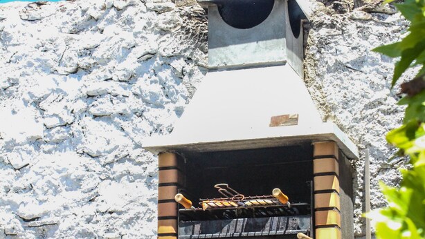 A stone wall with a brick oven and a tire. - Azenhas Rustic Beach House (Lisboa)