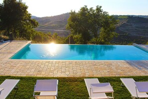 Une piscine rectangulaire offrant une vue dégagée sur un paysage vallonné en arrière-plan.