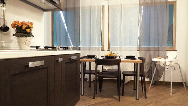 Cocina compacta con una isla central, una mesa de comedor con cuatro sillas y una trona.
