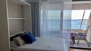 Un dormitorio con una cama, una mesita y una silla.