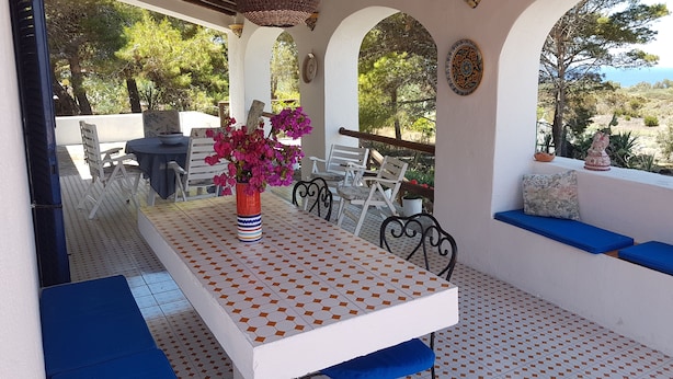 Une terrasse extérieure avec une table, des chaises et un luminaire suspendu.