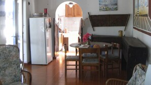 Une cuisine spacieuse avec un coin repas, des poutres apparentes en bois au plafond, un réfrigérateur et des meubles en osier.