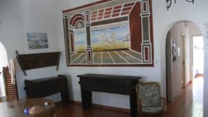 Une pièce décorée d’une fresque murale, avec un banc en bois, une chaise et une table.