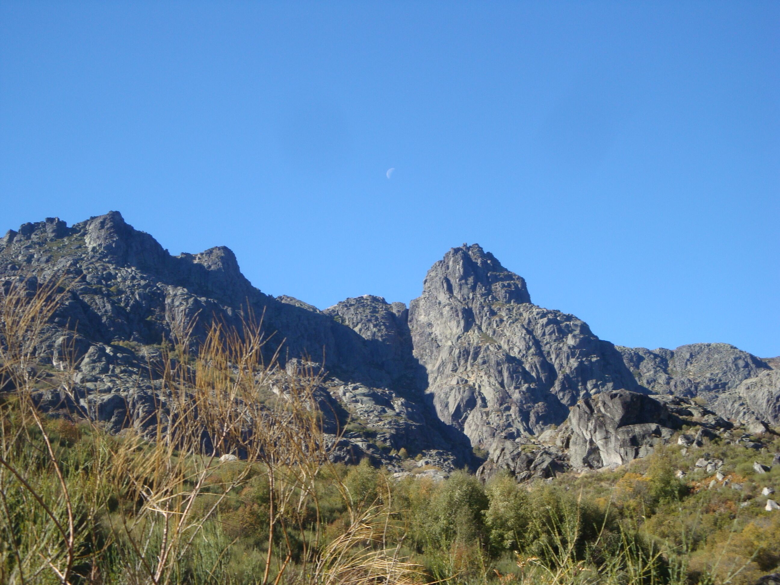 Un paisaje montañoso con terreno rocoso y vegetación escasa.