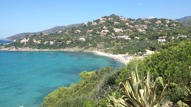 A coastal landscape with houses on a hillside overlooking the sea.