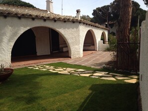 A courtyard with a white building featuring arched doorways and a tiled roof.