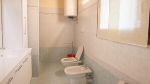 A bathroom with two toilets, a sink, and a shower. - Two bedroom apartment with pool view (Bassana)