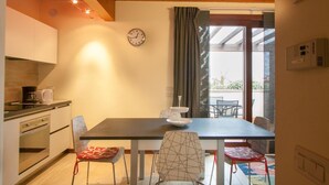 A cozy dining area with a table, chairs, and a clock on the wall. - Two bedroom apartment with pool view (Bassana)